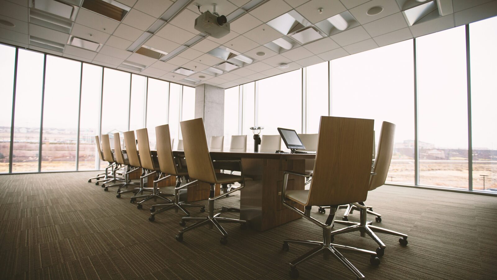 An oval wooden conference table surrounded by empty chairs
