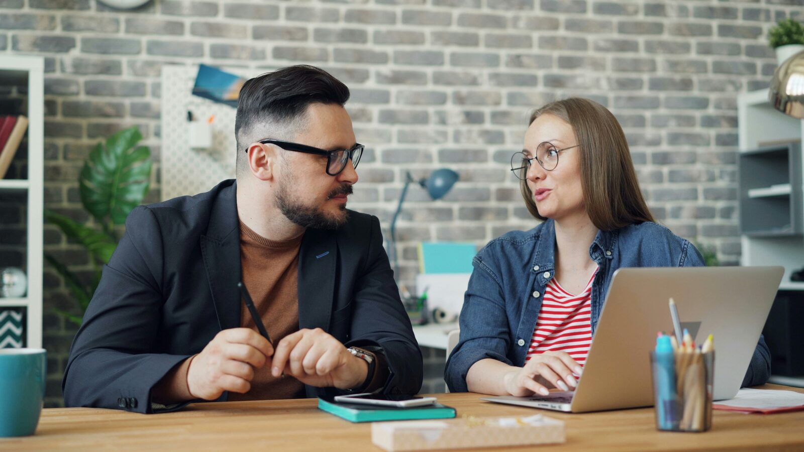 Two people sitting at a table looking together at a laptop screen