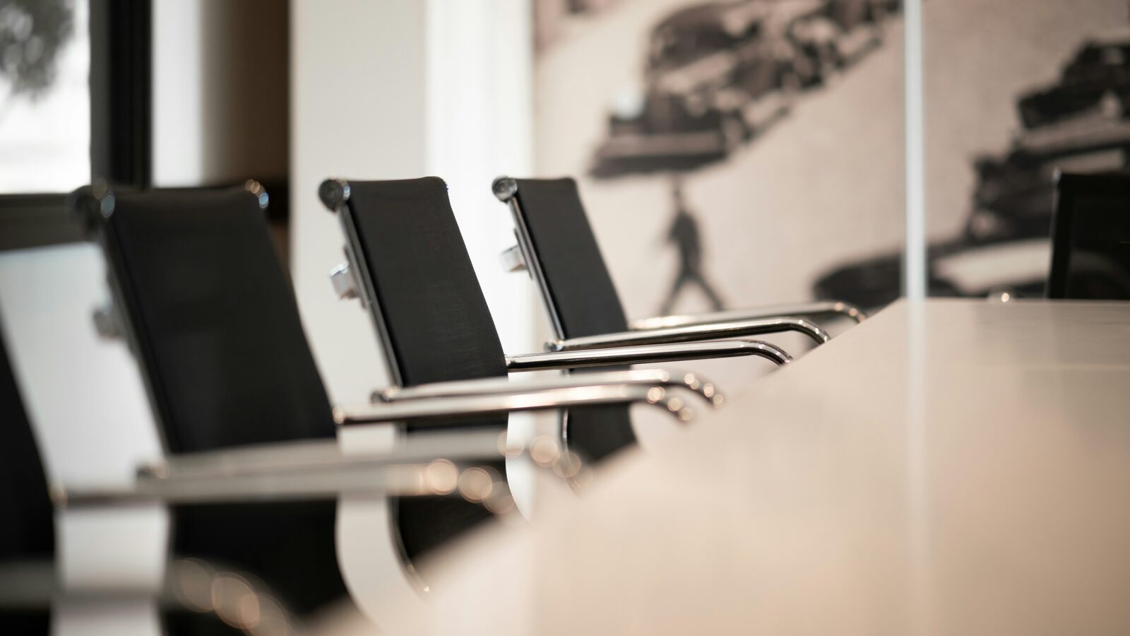 A row of black office chairs pulled up to an empty conference table