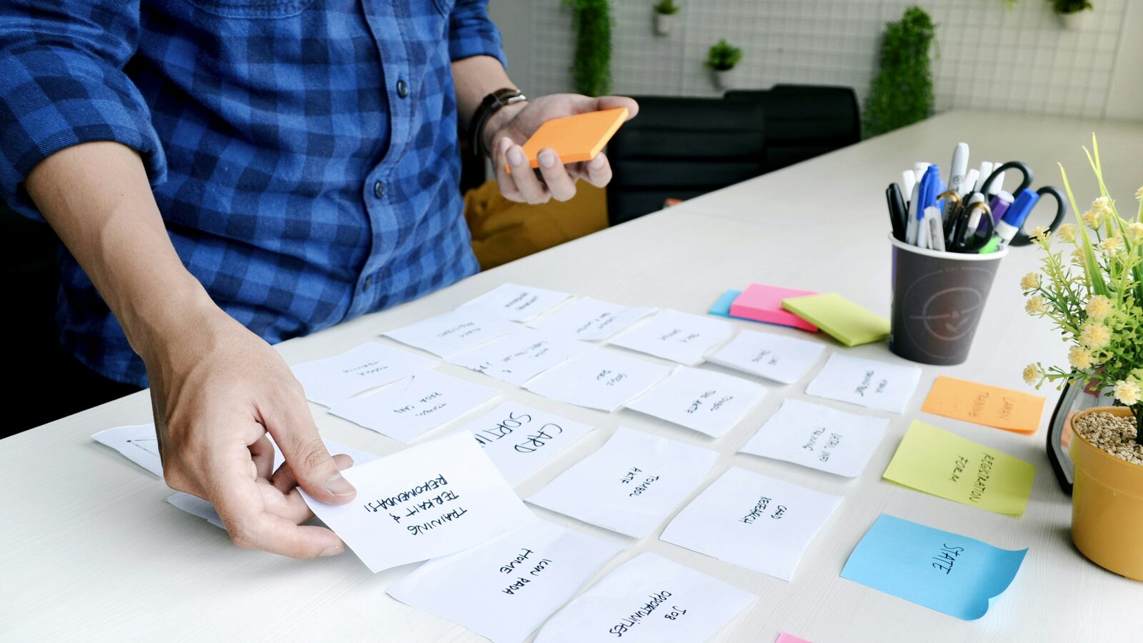 A hand placing a blank card among rows of cards sorted on a table