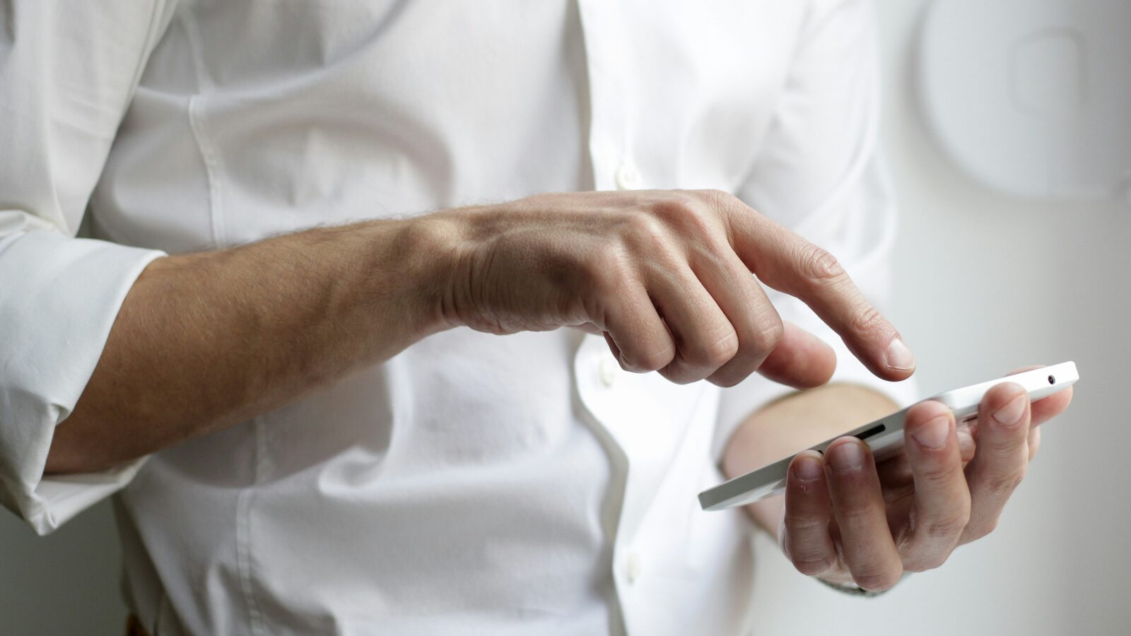 A person in a white shirt holding a smartphone in both hands