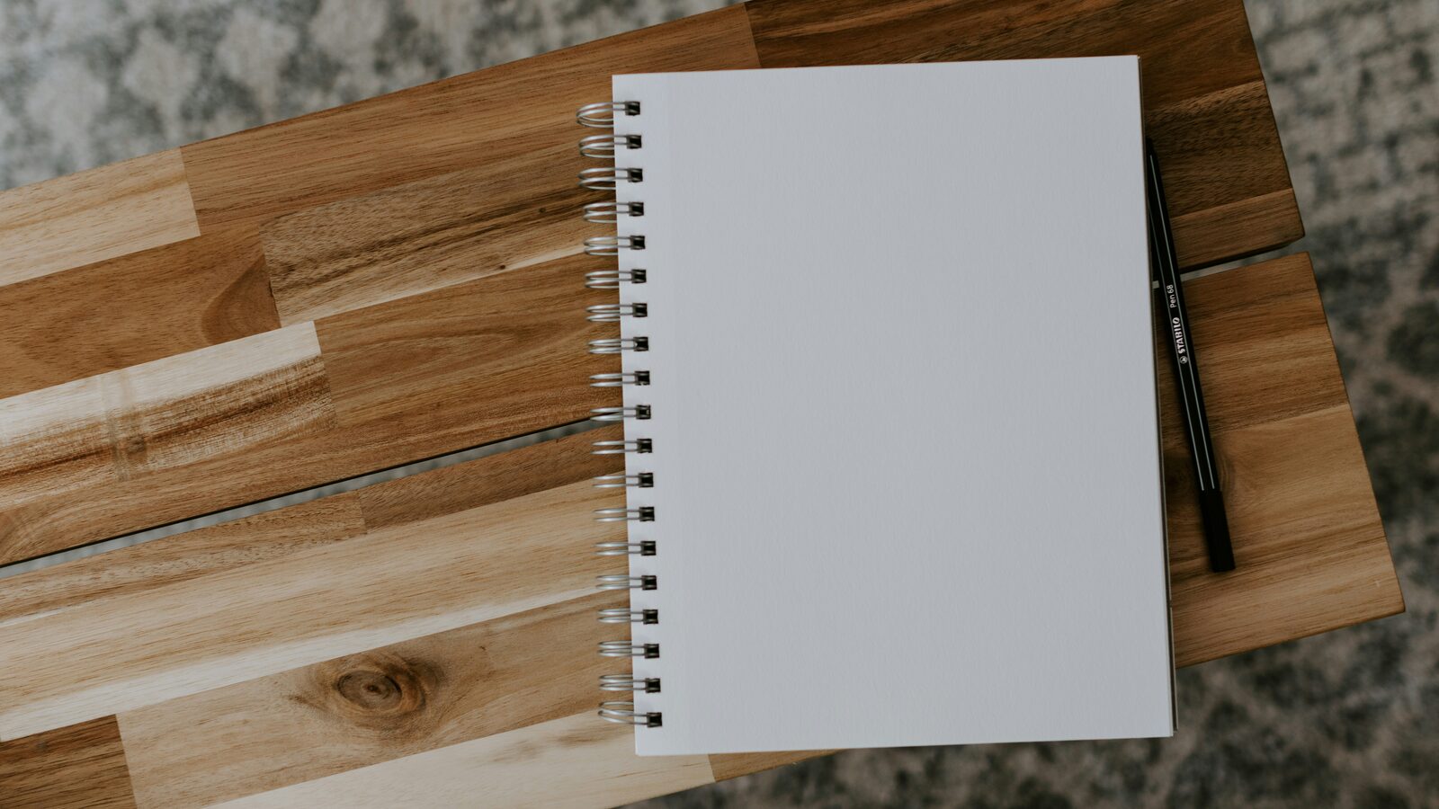 An open white spiral notebook on a brown wooden table